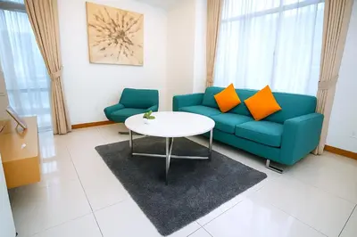 a living room with a blue couch and a table at Cormar Suites Kuala Lumpur in Kuala Lumpur