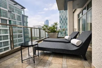 a balcony with a chair and a table and some buildings at Cormar Suites Kuala Lumpur in Kuala Lumpur
