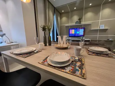 a dining room table with plates and wine glasses at ARCORIS, MONT KIARA by MK HOME in Kuala Lumpur