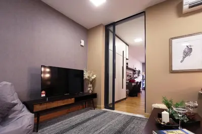 a living room with a flat screen tv on a wall at Lily and Loft - KL Gateway Bangsar LRT, WIFI, Netflix in Kuala Lumpur
