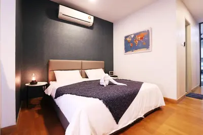 a white dog laying on a bed in a bedroom at Lily and Loft - KL Gateway Bangsar LRT, WIFI, Netflix in Kuala Lumpur