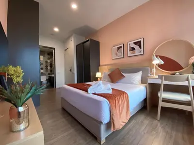 a bedroom with a bed and a desk with a mirror at Ceylonz Seasonal Suites in Kuala Lumpur