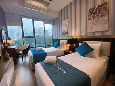a hotel room with two beds and a desk at Ceylonz Starlight Suites Bukit Bintang in Kuala Lumpur