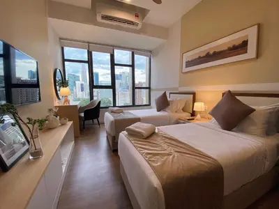 a hotel room with two beds and a desk at Ceylonz Starlight Suites Bukit Bintang in Kuala Lumpur