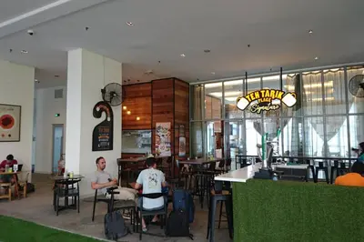 two people sitting at tables in a restaurant at KLCC Regalia Suites Infinity Pool Kuala Lumpur in Kuala Lumpur