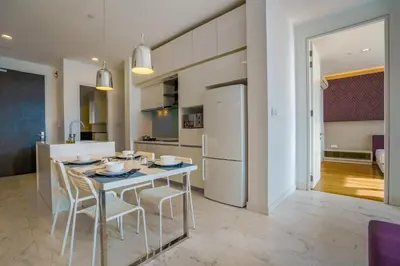 a kitchen with a table with chairs and a refrigerator at Yemala Suites at Platinum KLCC in Kuala Lumpur