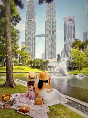 two women sitting on the grass in front of a fountain at KLCC City SkySuites in Kuala Lumpur