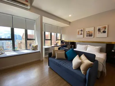 a living room with a blue couch and windows at Ceylonz Lifestyle Suites @ Bukit Bintang in Kuala Lumpur