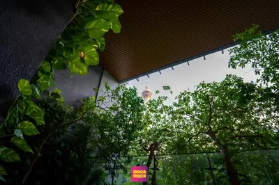 a building with a pink sign in front of trees at Ceylonz Suites KLCC Rooftop Infinity Pool KL Tower View in Kuala Lumpur