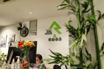 a girl sitting at a table in a room with plants at Rain Forest Hotel in Kuala Lumpur