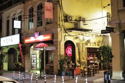 a city street with tables and chairs in front of a building at Rain Forest Hotel in Kuala Lumpur