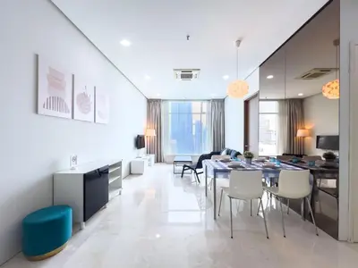 a dining room and living room with a table and chairs at Soho Suites KLCC by GuestHouse in Kuala Lumpur