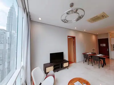 a living room with a television and a table with chairs at Soho Suites KLCC by GuestHouse in Kuala Lumpur
