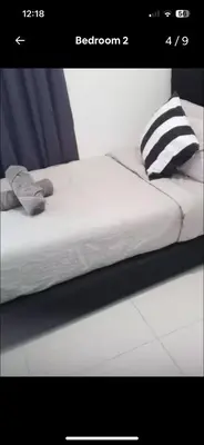 a white bed with a black and white pillow at Robertson PanoramaKL Suites in Kuala Lumpur