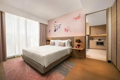 a bedroom with a large white bed and a kitchen at Capri by Fraser, Bukit Bintang in Kuala Lumpur