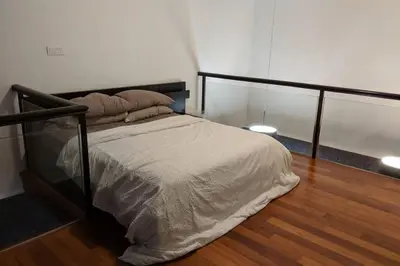 a bedroom with a bed and a wooden floor at Cozy designer loft near KL city center in Ampang