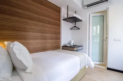 a bedroom with a white bed with a wooden headboard at 12FLY Hotel Kuala Lumpur in Kuala Lumpur