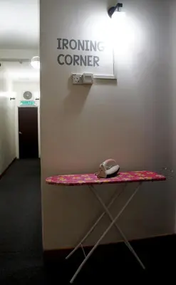 a ironing corner with a computer mouse sitting on a table at Maple Inn in Kuala Lumpur