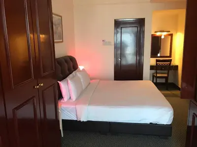 a bedroom with a bed with white sheets and pink pillows at Fantazya Suites Times Square in Kuala Lumpur