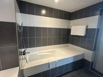 a bath tub in a bathroom with blue and white tiles at Alamis City Kuala Lumpur - Formerly EDC Hotel Kuala Lumpur in Kuala Lumpur