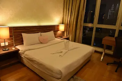 a bedroom with a bed with two lamps and a window at Regalia Residence @ KLCC View Sky Pool by KC in Kuala Lumpur