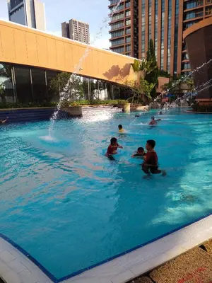 a group of people swimming in a swimming pool at Times Square Grand Service Suite in Kuala Lumpur