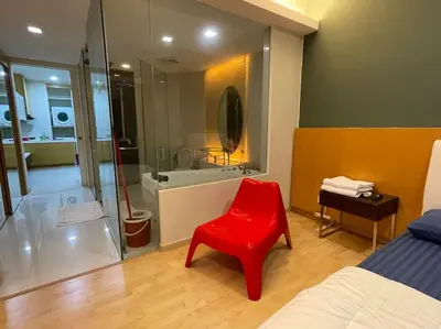 a red chair in a bedroom with a bathroom at Stylish Romantic Couples Getaway at KL City 1419 in Kuala Lumpur