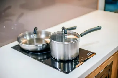 two pots and pans on a stove in a kitchen at 188 Suites KLCC by CoBNB in Kuala Lumpur