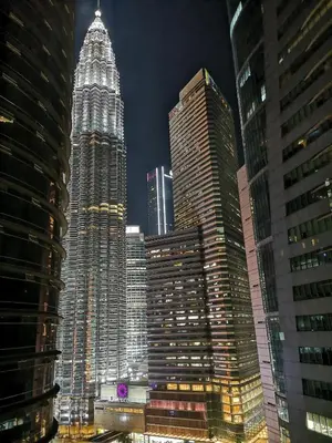 a group of tall buildings in a city at night at GH KLCC Apartment by GuestHouse in Kuala Lumpur