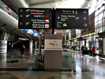 an airport terminal with signs and people walking around at KL Sentral Loft, EST Bangsar #1, LRT in Kuala Lumpur