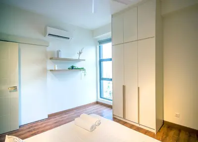 a bedroom with white cabinets and a window at Near MITEC, Arte Mont Kiara by Cobnb in Kuala Lumpur