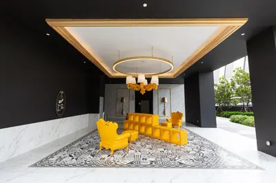 a lobby with yellow chairs and a chandelier at Near MITEC, Arte Mont Kiara by Cobnb in Kuala Lumpur