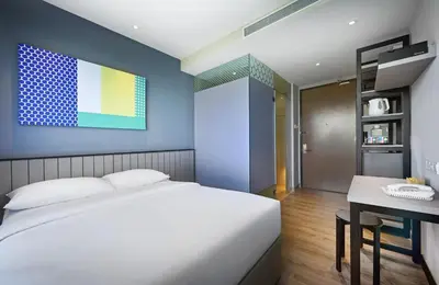 a bedroom with a white bed and a table at Hotel Komune Living & Wellness Kuala Lumpur in Kuala Lumpur