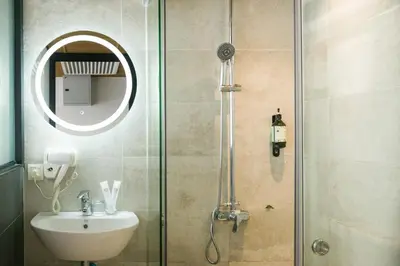 a bathroom with a shower with a sink and a mirror at Santa Grand Classic Kuala Lumpur, Chinatown in Kuala Lumpur