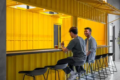 two men sitting at a bar in a yellow room at lyf Chinatown Kuala Lumpur in Kuala Lumpur