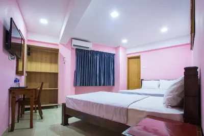 a bedroom with two beds and a table and a desk at MK Inn Hotel in Kuala Lumpur