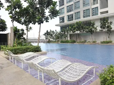 a row of white wicker chairs next to a swimming pool at MyCribKL The Robertson 2 Bedroom Bukit Bintang in Kuala Lumpur