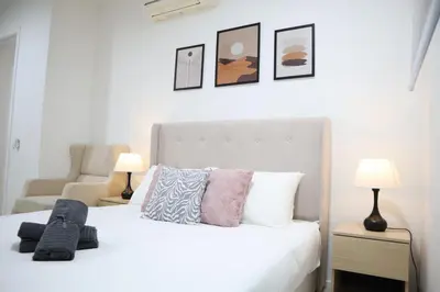 a bedroom with a white bed with pillows and two lamps at New Arcoris 6 Pax 2 BR with Pool View Mont Kiara - BOHO in Kuala Lumpur