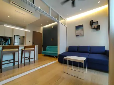 a living room with a blue couch and a kitchen at Star Suite 5min Walk to KLCC Netflix in Kuala Lumpur