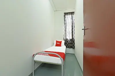 a room with a chair with a red pillow on it at Hotel O Sri Rampai Metro Hostel in Kuala Lumpur