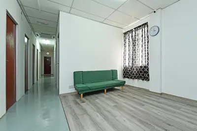 a green couch in an empty room with a clock at Hotel O Sri Rampai Metro Hostel in Kuala Lumpur