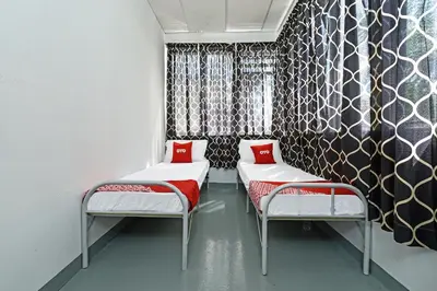 a room with two beds with red pillows at Hotel O Sri Rampai Metro Hostel in Kuala Lumpur