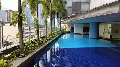 a swimming pool on the roof of a building with palm trees at Taragon BBCC in Kuala Lumpur