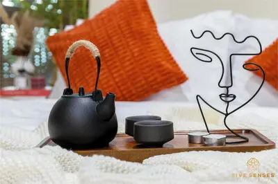 a tea pot and cups on a tray on a bed at The Colony & The Luxe, Kuala Lumpur by Canopy Lives in Kuala Lumpur
