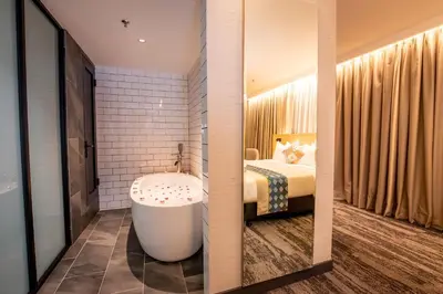 a bathroom with a tub and a bedroom with a bed at Santa Grand Signature Kuala Lumpur in Kuala Lumpur
