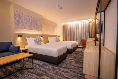 a hotel room with two beds and a couch at Santa Grand Signature Kuala Lumpur in Kuala Lumpur