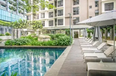 a pool with chairs and umbrellas next to a building at 188 Suites KLCC by Signature Apartment in Kuala Lumpur