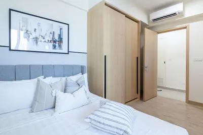a bedroom with a white bed with a picture on the wall at Colony @ Kampung Baru by Plush in Kuala Lumpur