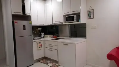 a small kitchen with white cabinets and a refrigerator at Summer Suites Klcc by Malenehom in Kuala Lumpur