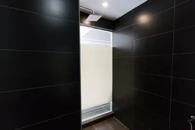 a bathroom with black walls and a glass shower door at Hotel 99 Kuala Lumpur City in Kuala Lumpur